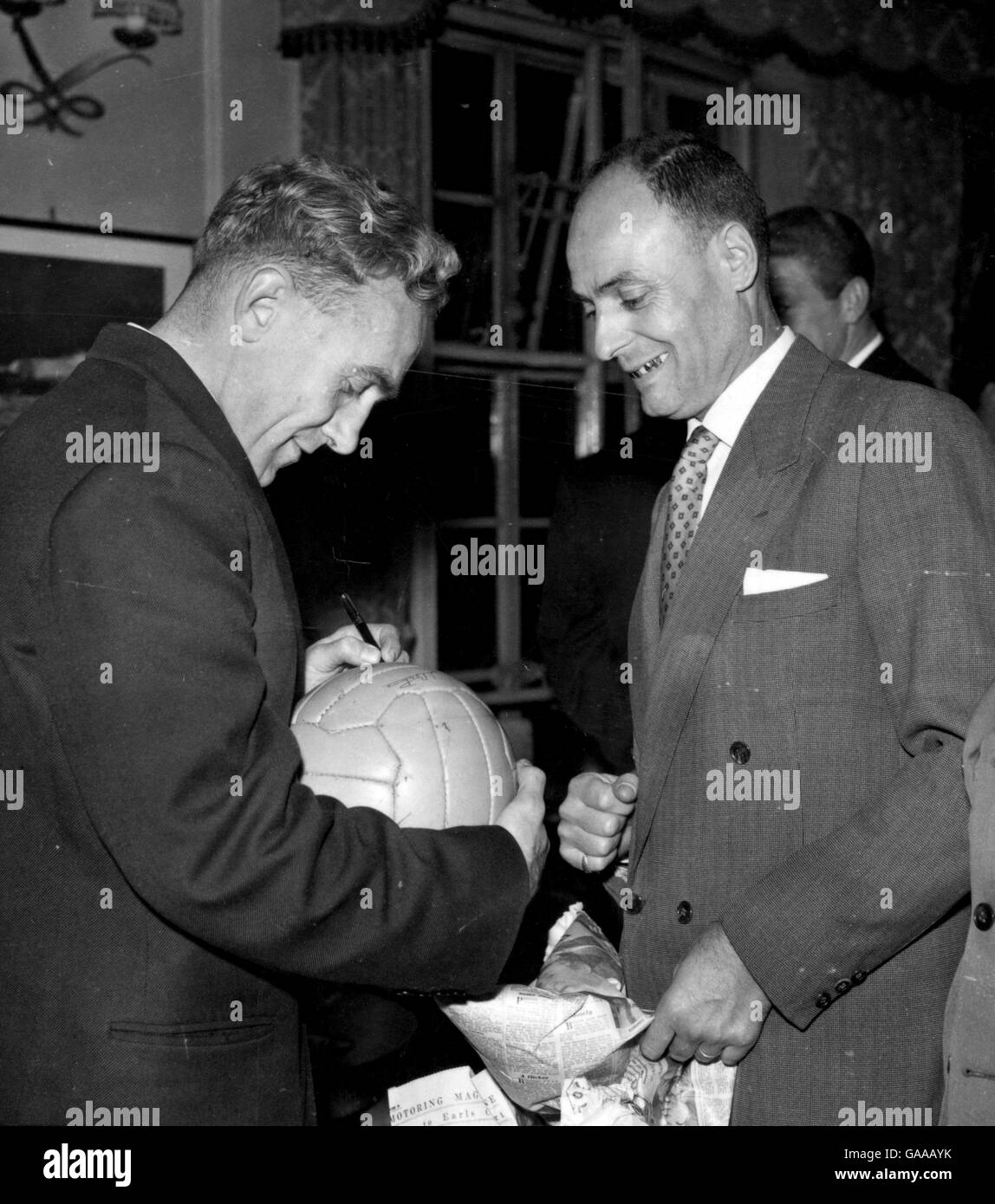 England captain Billy Wright autographs a ball for referee Maurice Guigue. Stock Photo