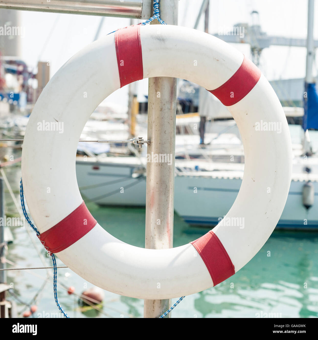 White life buoy hanging from a railing at the port. Stock Photo