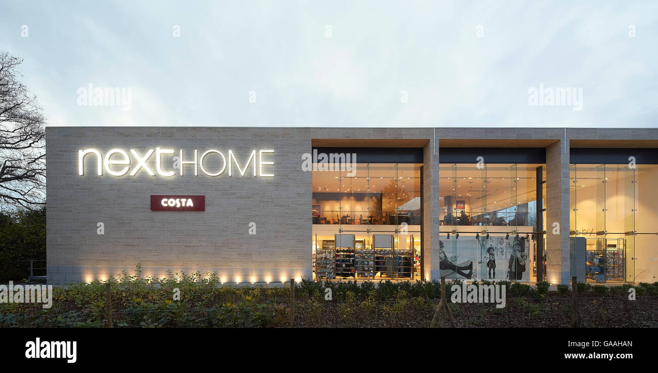 Exterior facade with logo and full-height glazing to interior. Next -  Home and Garden Stores, Southampton, United Kingdom. Architect: Stanton Williams, 2014. Stock Photo