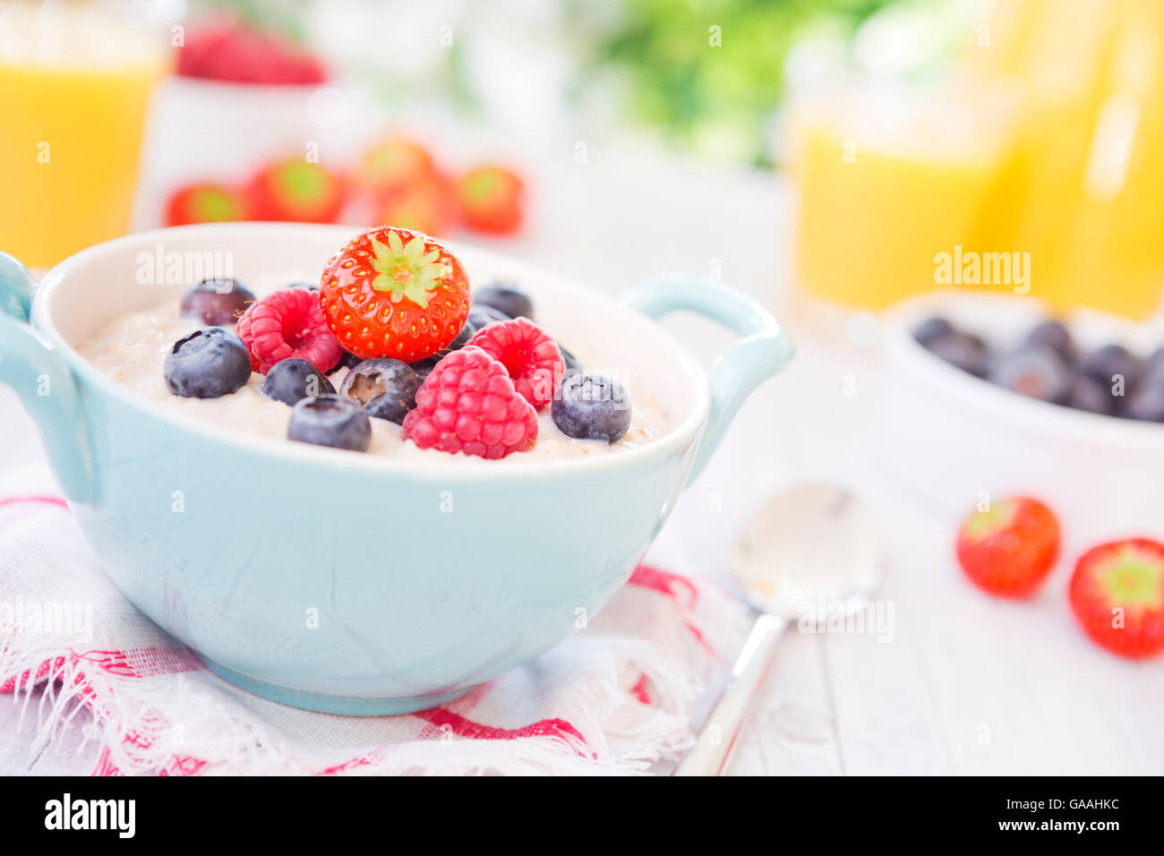 A bowl with homemade oatmeal porridge with fresh fruit on a rustic outdoor table. Stock Photo