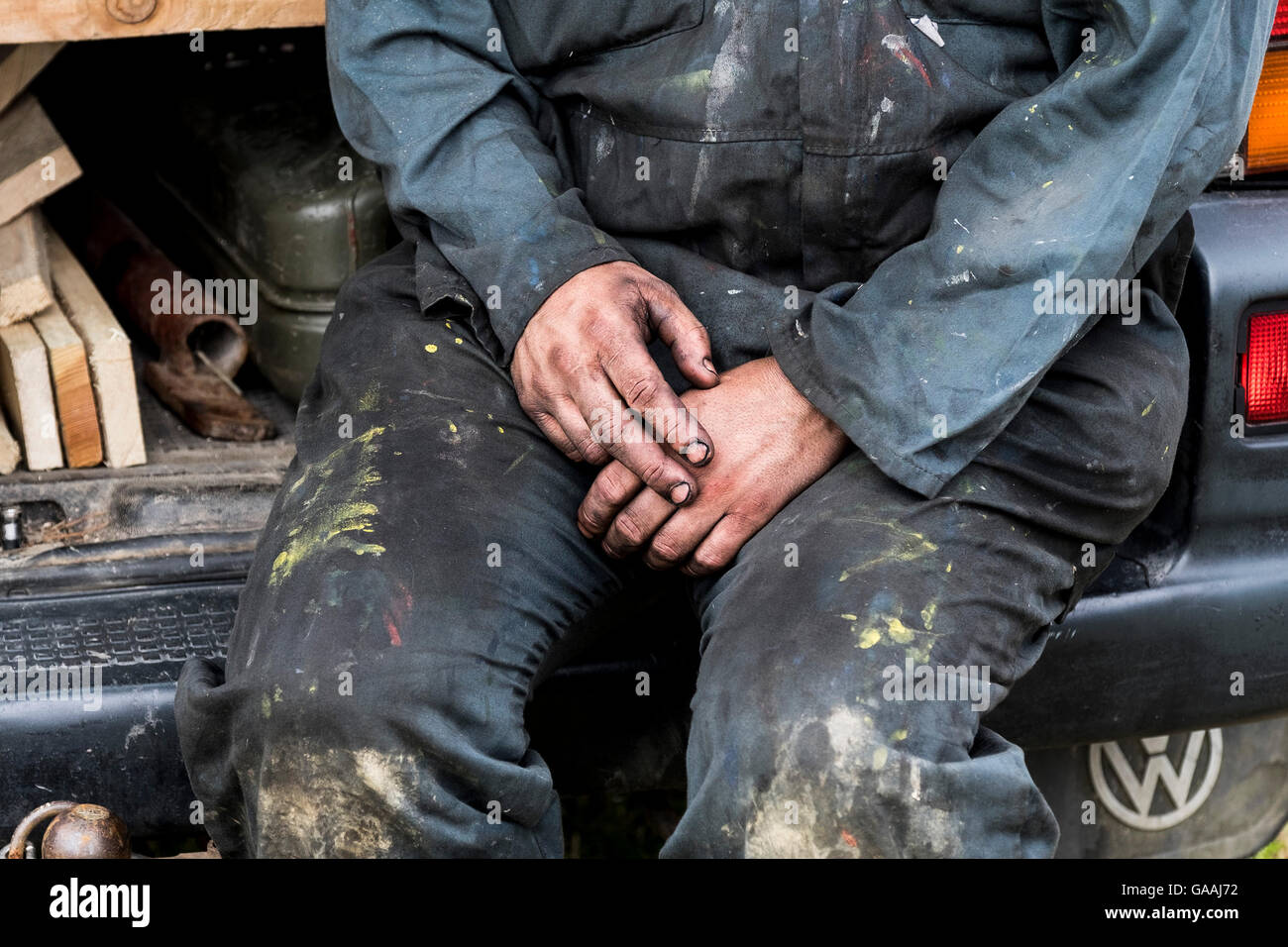 The oil covered hands and dirty overalls of a manual worker. Stock Photo