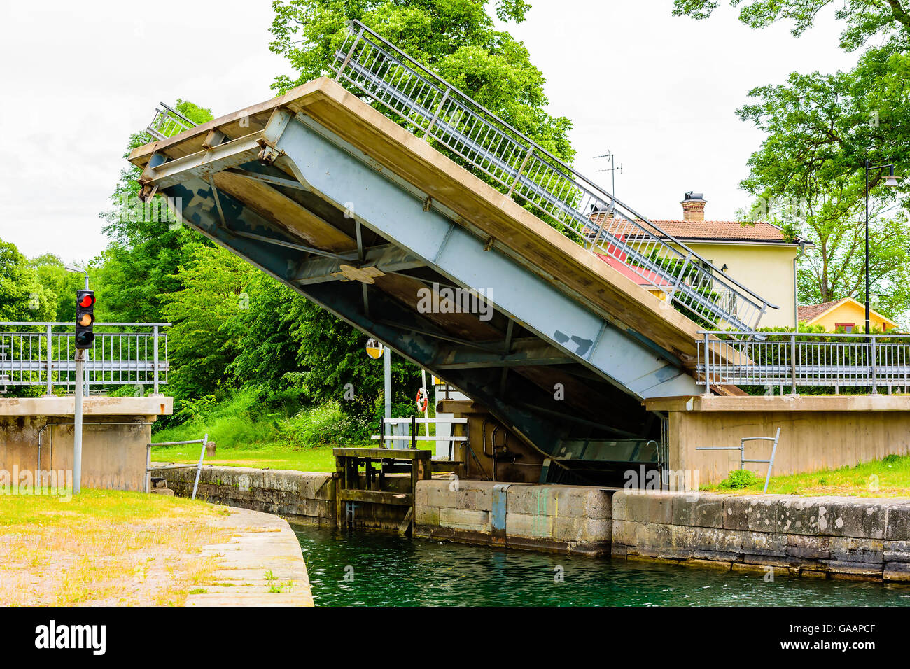 One section of a road crossing a canal is lifted up as a movable bridge. Traffic light signal to boats to stop and be ready for Stock Photo