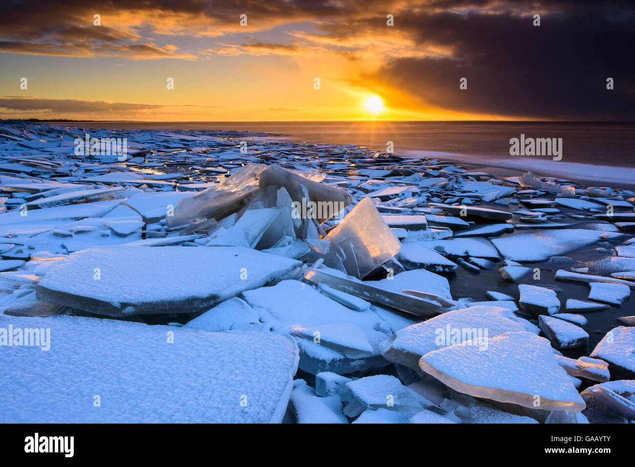 Broken ice covered in snow at sunset, on the shore of Lake Vortsjarv, gathered to shore by extreme winds, Estonia. December 2014. Stock Photo