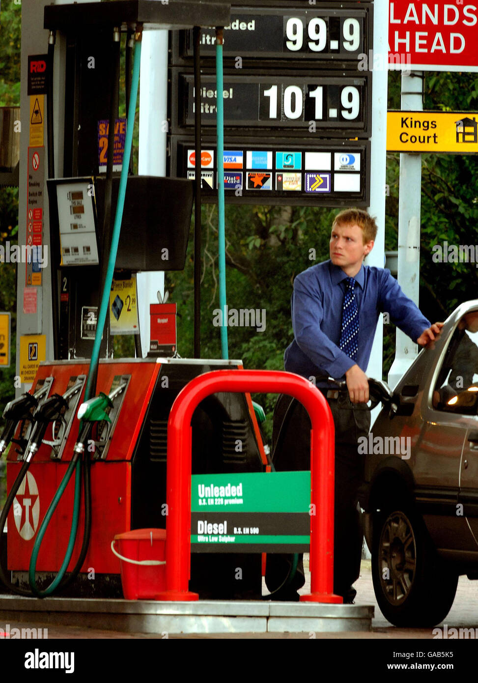 A motorist refuels at a petrol station in Ashby de la Zouch, Leicetsershire. The new prices of fuel can be seen displayed on the forecourt with diesel fuel at 1.01 a litre and unleaded fuel 99.9 pence a litre. Stock Photo