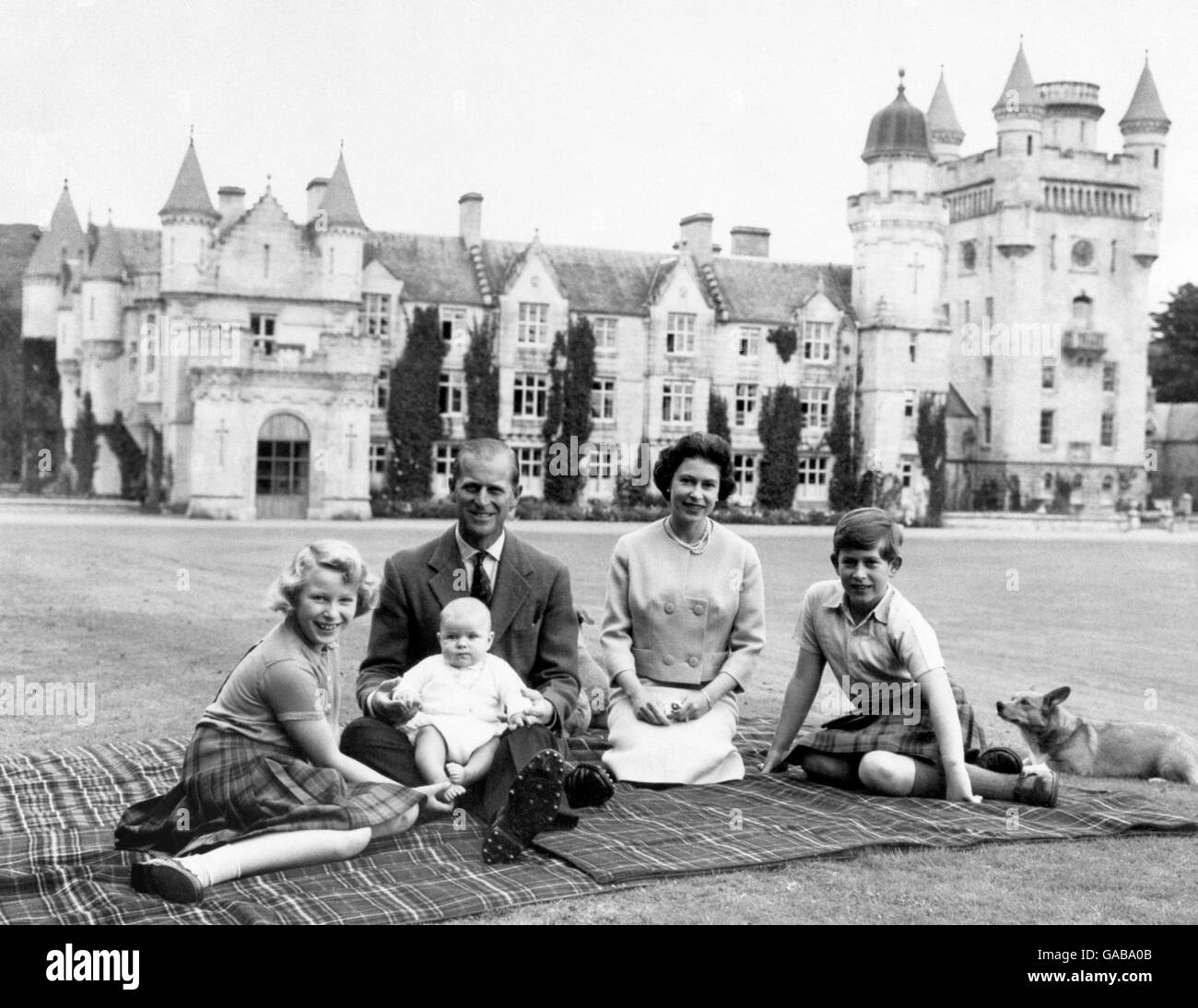 Making a happy group on the lawns at Balmoral, are the Queen, the Duke of Edinburgh and their three children Princess Anne, Prince Charles and baby Prince Andrew, on his father's knees. Stock Photo