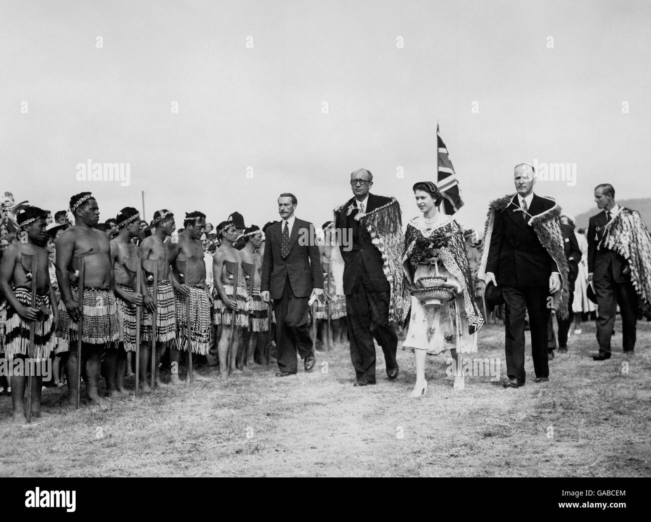 The Queen, wearing the Korowai Cloak, symbol of paramount rank, and carrying a two tier basket, inspects Maoris at the reception held in her honour in Arawa Park, Rotorua, during the Royal tour of New Zealand. Stock Photo