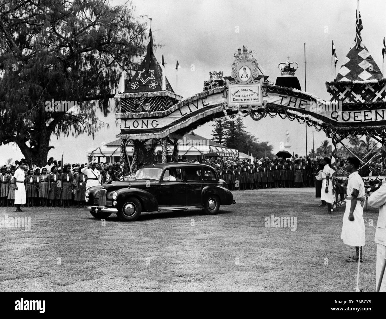 A car of the Royal procession passing through the ornate triumphal arch, part of the decorations for the visit of the Queen and the Duke of Edinburgh to Nukualofa, capital of Queen Salote, on the island of Tonga during the Commonwealth tour. Stock Photo