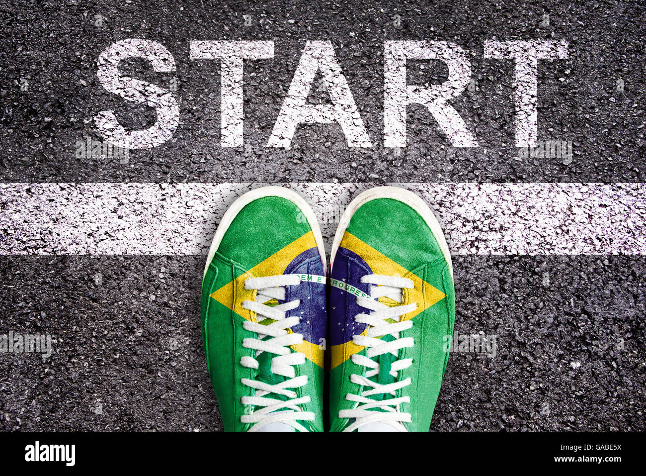 Word Start written on an asphalt road with legs and shoes colored with the brazilian flag Stock Photo