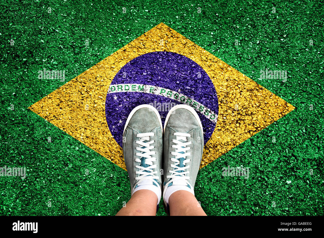 Legs and shoes standing on a floor colored with the brazilian flag Stock Photo