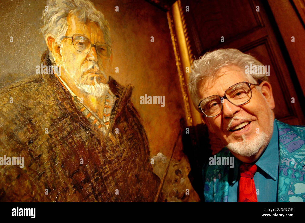 Musician and TV star Rolf Harris poses in front of his self portrait