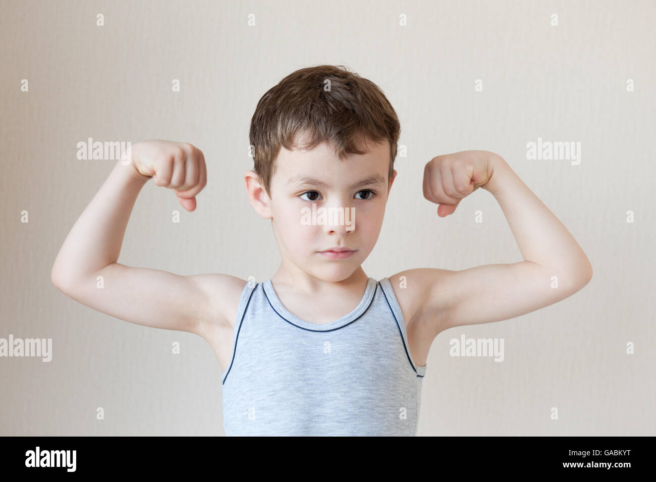strong little boy in t-shirt showing muscles Stock Photo - Alamy