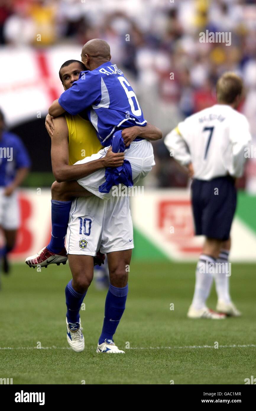 Roberto Carlos congratulates Rivaldo after scoring Brazil's opening goal with a dejected England captain, David Beckham Stock Photo