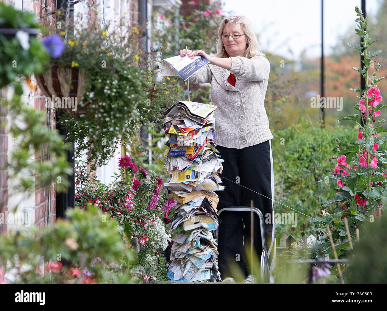 Artist Anne Cohen from Fenham, Newcastle, stands in her garden with a five foot tall metal spike, covered in all of the junk mail that has been delivered to her door by hand since January 1 this year. Stock Photo