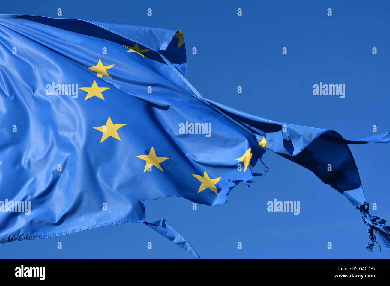 The european union twelve star flag torn and with knots in the wind on blue sky Stock Photo