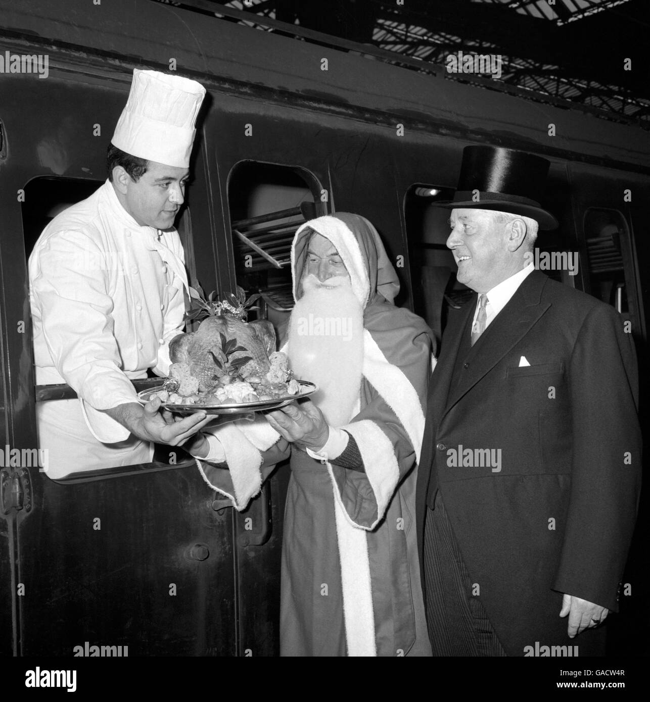 Chef Pedro Carol is seen off from Liverpool Street Station, London, by Station Master H.B Onyon and Father Christmas (played by Victor Large) on the 'Christmas Special' bound for Turkey Street, the re-opened station on the Eastern Region's line to Bishop's Stortford. On arrival, farmers forming the British Turkey Federation were to distribute turkeys to the inhabitants of Turkey Street from a public house called 'The Turkey'. Stock Photo