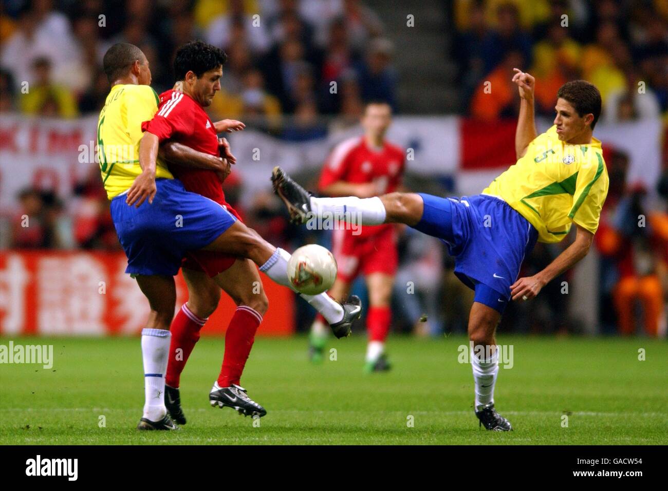 Soccer - FIFA World Cup 2002 - Semi Final - Brazil v Turkey. Turkey's Yildiray Basturk holds of the challenges of Brazil's Gilberto Silva (l) and Edmilson (r) Stock Photo