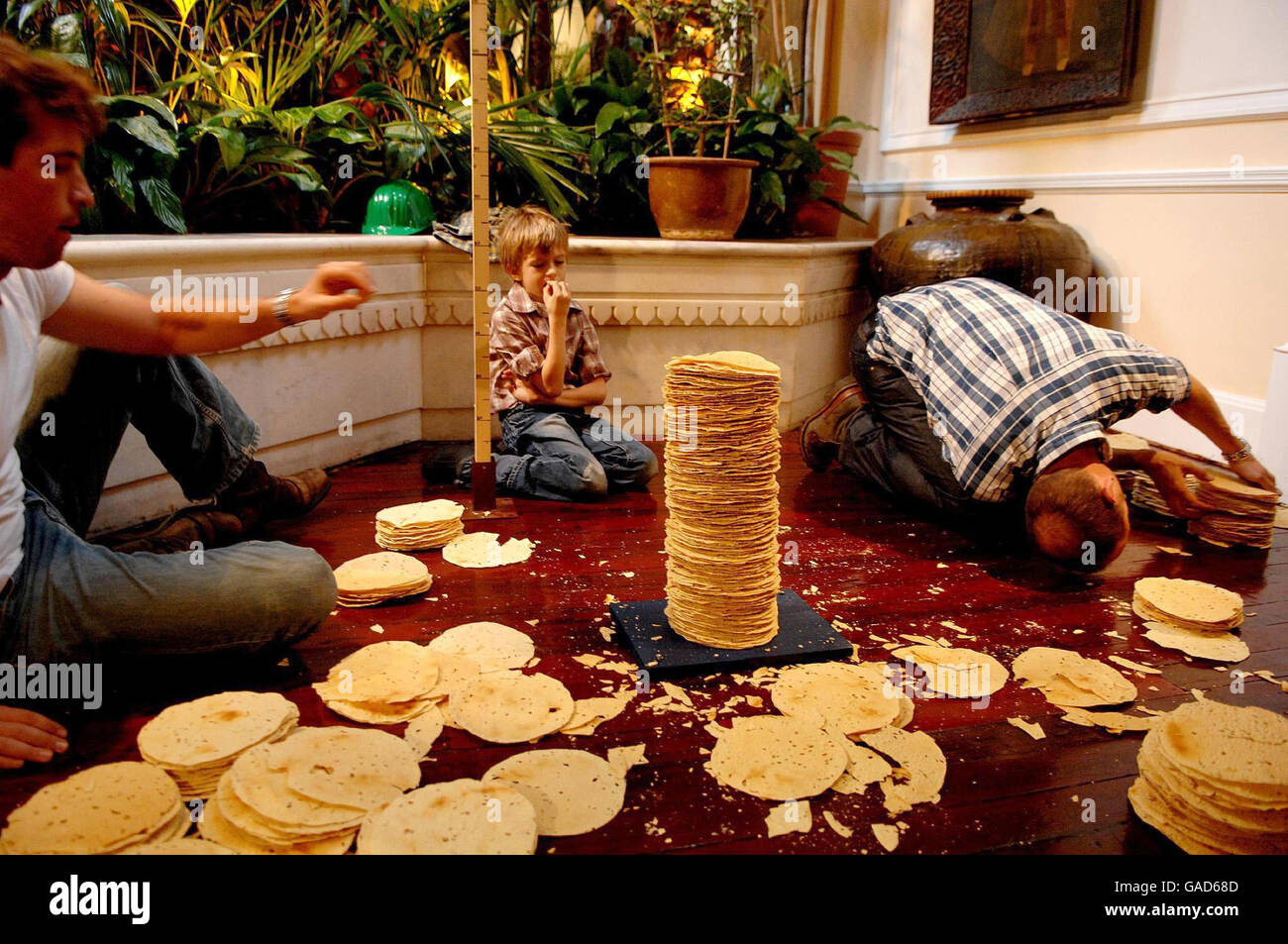 Seven-year-old Marley Bradbury (centre) watches as his father, Richard Bradbury (right), and Kristopher Browcott (left) attempt to break the world record for the tallest stack of poppadoms at the La Porte des Indes restaurant in Marble Arch, London, during the Guinness World Records Day. Stock Photo