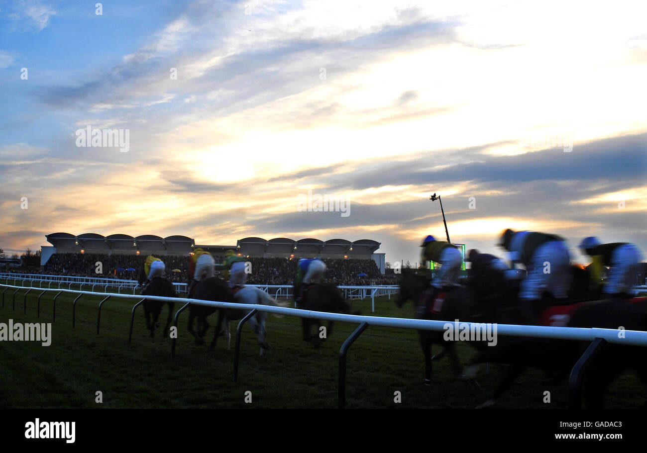 The sun begins to set as the runners in The Servo Computer Services Trophy Handicap Steeple Chase turn away from the main grandstand to start the second circuit at Cheltenham Racecourse. Stock Photo