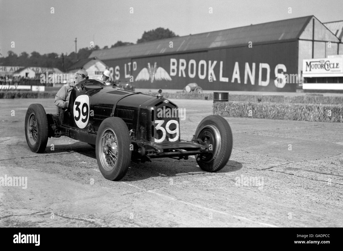Harry Rose passes by the Brooklands hangar during the British Empire Trophy Race. Stock Photo
