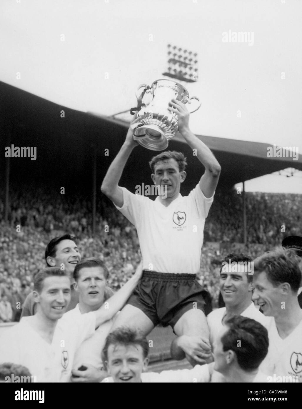 Tottenham Hotspur captain Danny Blanchflower holds the FA Cup aloft as he is chaired by teammates (l-r) Cliff Jones, Bill Brown, Peter Baker, Terry Dyson, Les Allen, Bobby Smith and John White Stock Photo