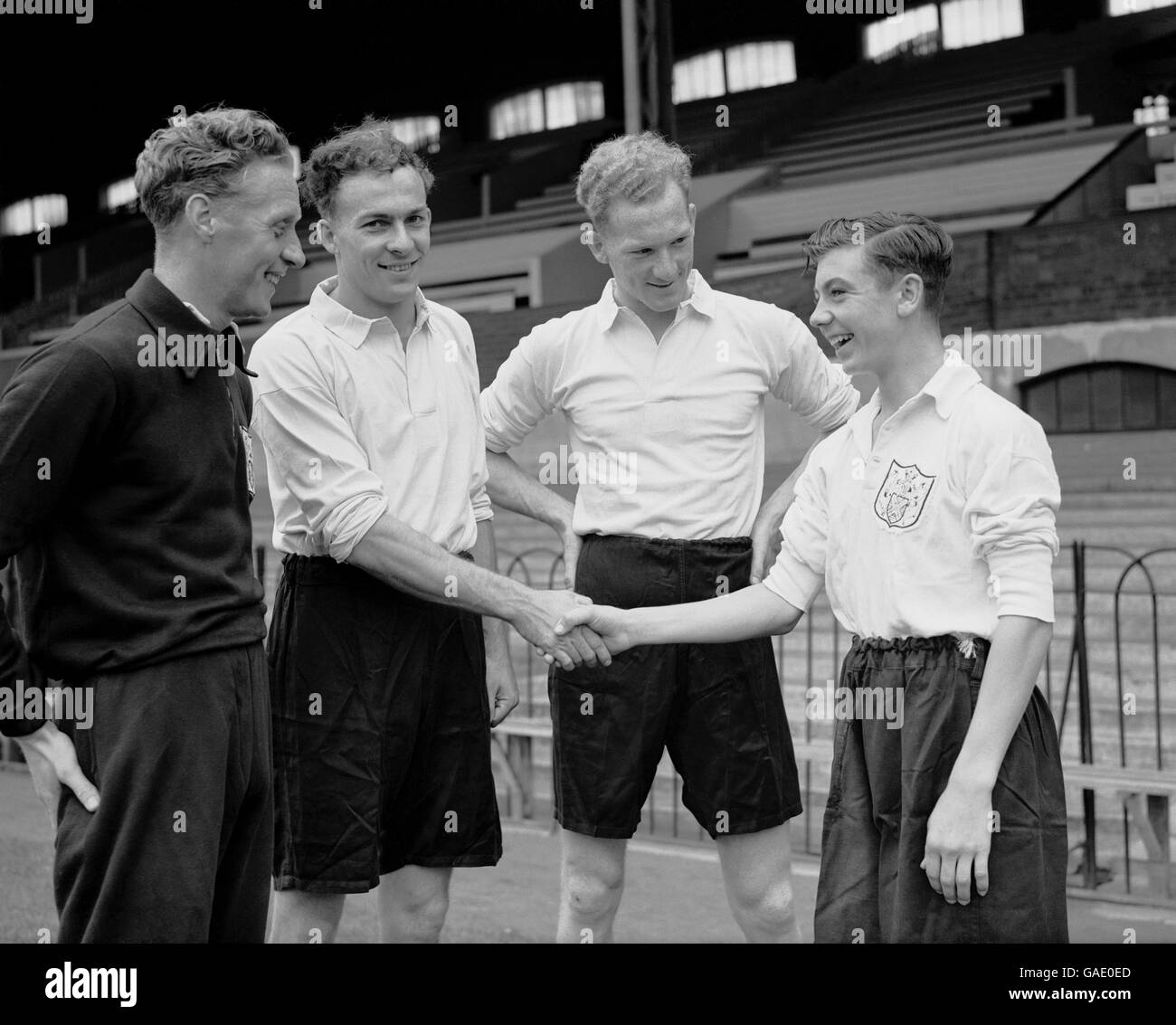 Fifteen year old Johnny Haynes, Edmonton schoolboy international forward, meeting other new signings (left to right) Archie Macaulay (wing half from Arsenal) and brothers Eddie and Reg Lowe (both from Aston Villa) at the Club when Fulham began training for the new football season at Craven Cottage. Johnny is to work in the club offices as he cannot sign professional forms until he reaches seventeen. Stock Photo