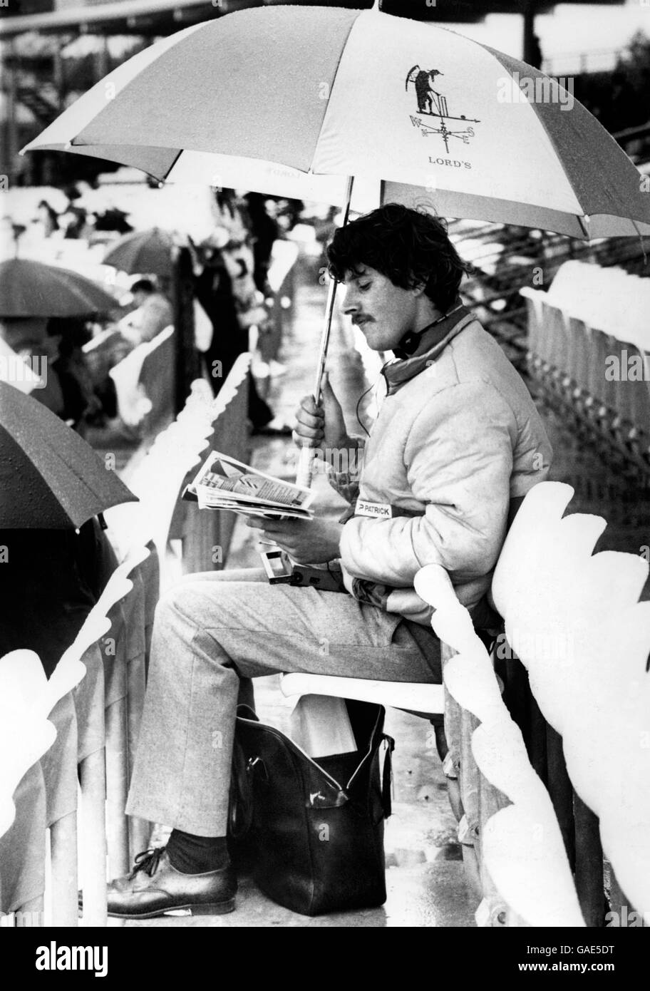 Cricket - Second Test - England v Pakistan - Day Four - Lord's. A Lord's cricket fan sits with his umbrella as play is abandoned for the day Stock Photo