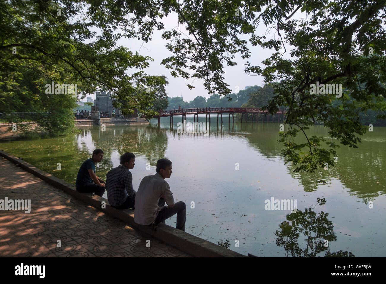 Sitting by the  Hoan Kiem Lake, The Huc Bridge beyond, Ha Noi, Viet Nam Stock Photo