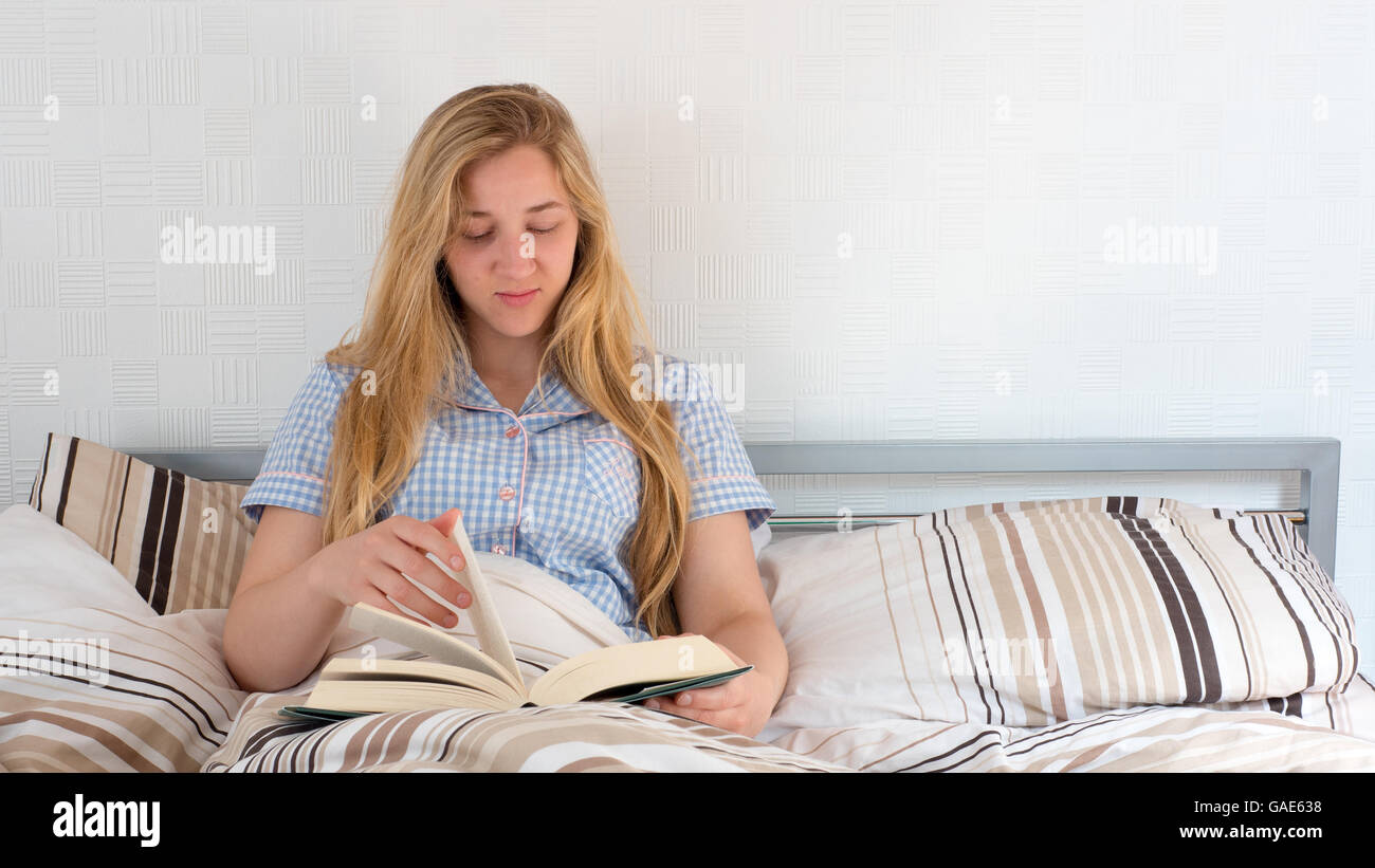 pretty girl reading book while lying in bed Stock Photo Alamy