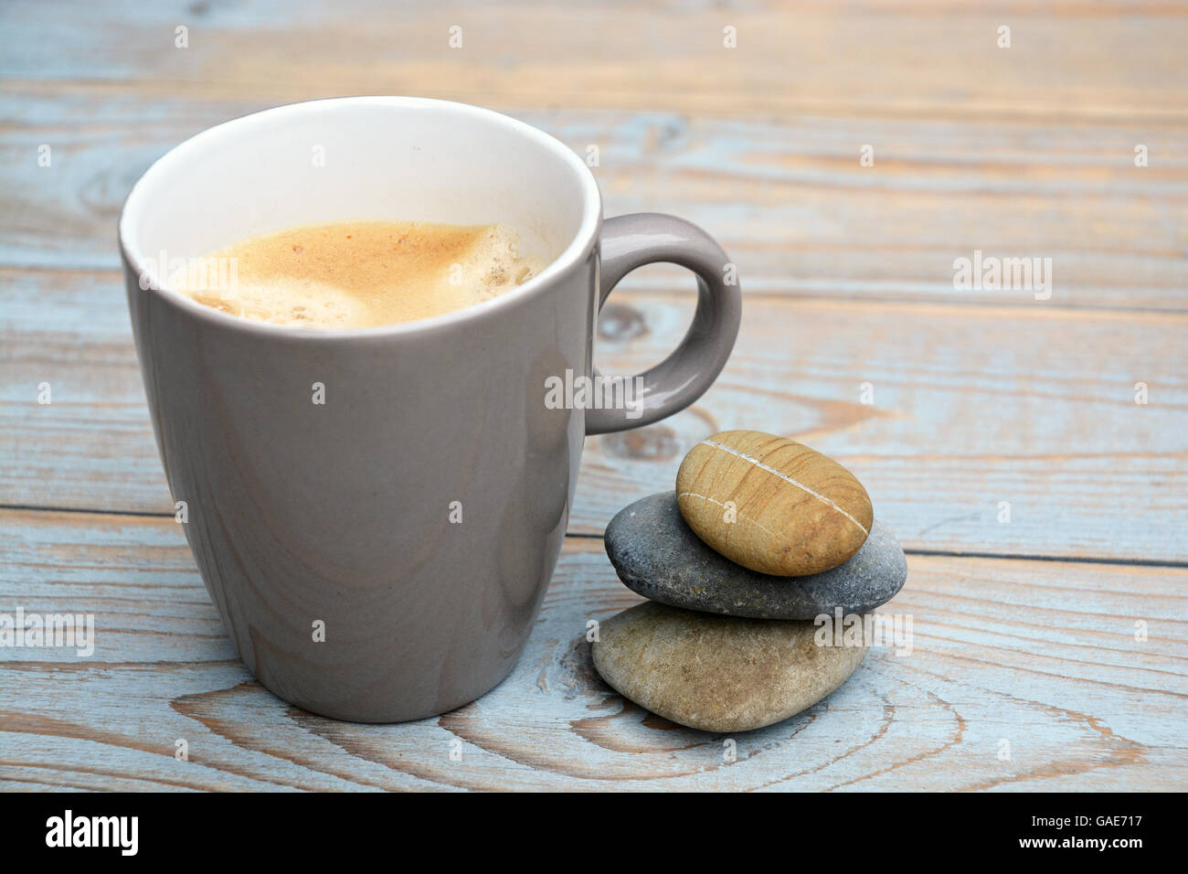 Cup of coffee in a mug on a old wooden background with three zen cairn stones Stock Photo