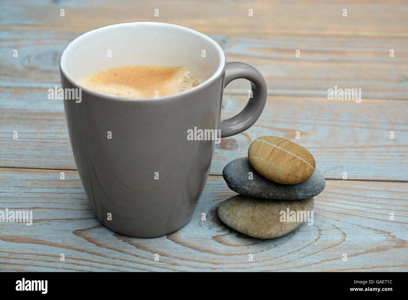Cup of coffee in a mug on a old wooden background with three zen cairn stones Stock Photo