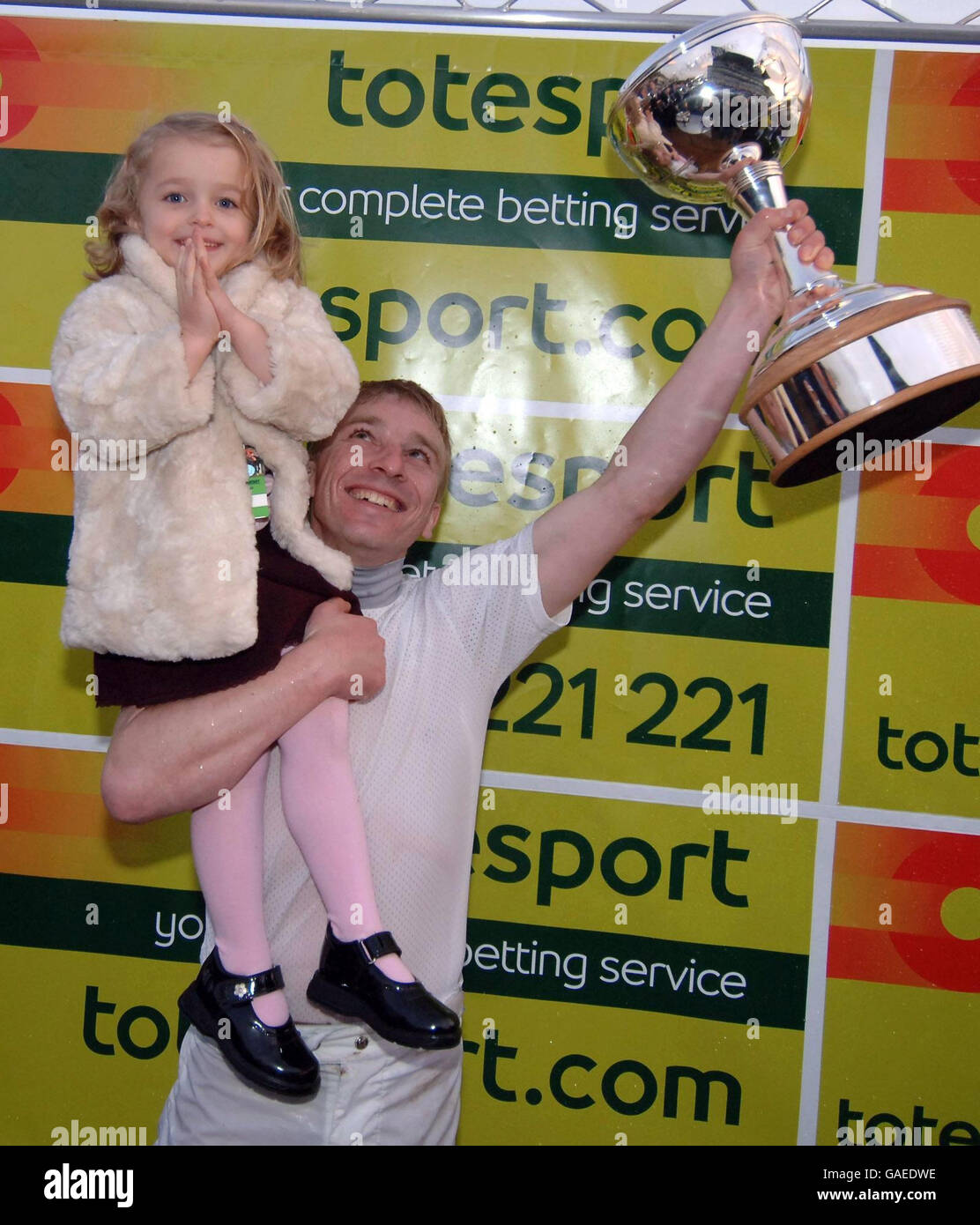 Jockey Seb Saunders holds his daughter Darcy and the Jockeys Championship Trophy which he shared with Jamie Spencer on the final day of the Turf flat Season at Doncaster Racecourse. Stock Photo