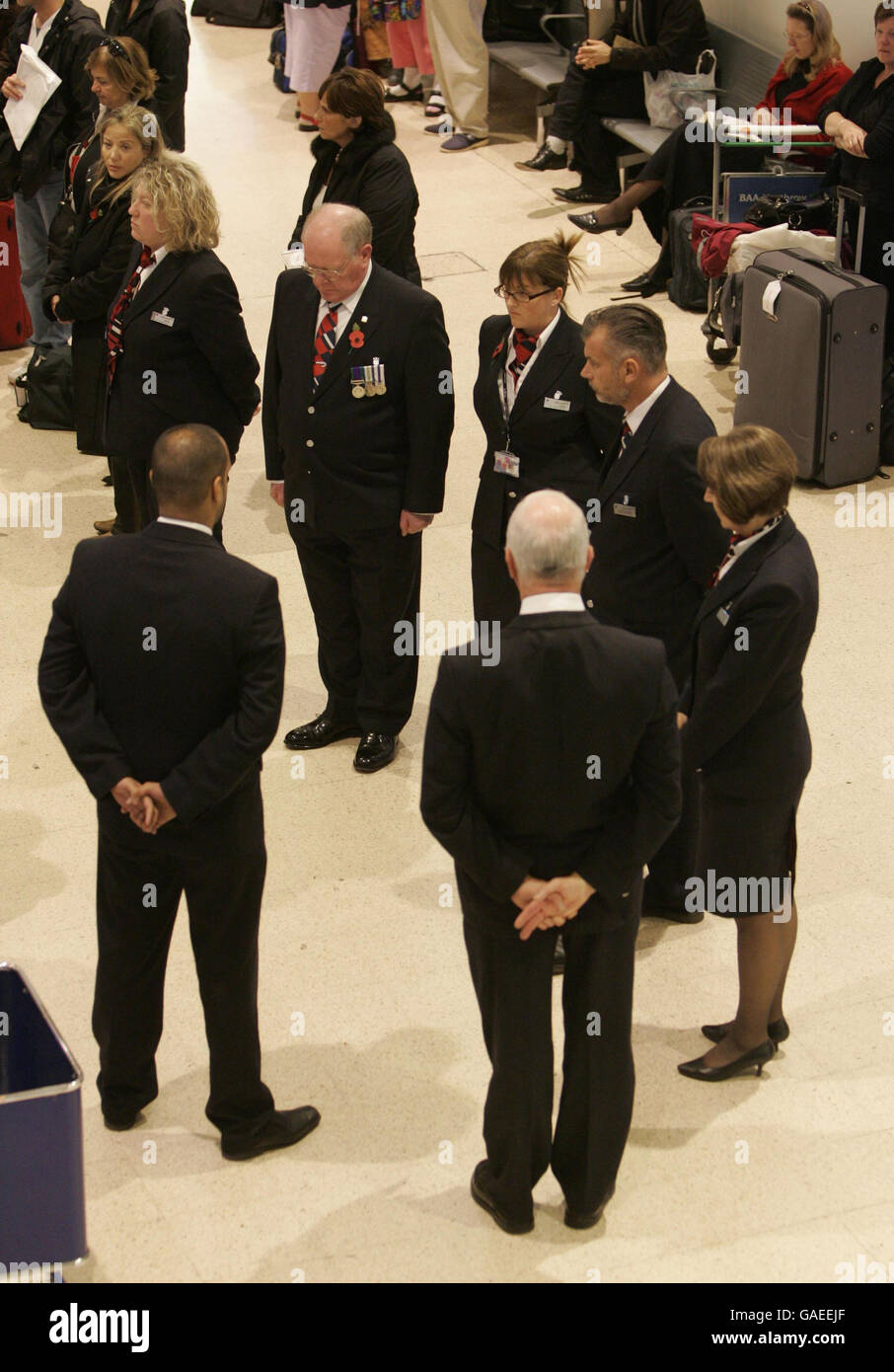 British Airways check-in staff stand during the 2 minutes silence for Remembrance Sunday in Heathrow's Terminal 1, west London. Stock Photo