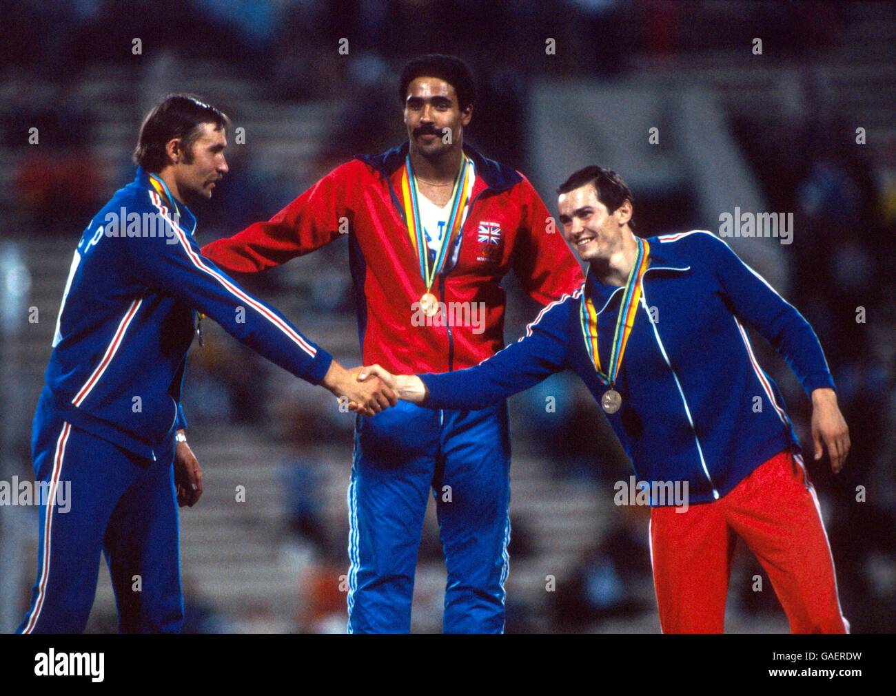 Gold medallist Daley Thompson of Great Britain (c) magnanimously pats USSR's Yuriy Kutsenko (silver, l) and Sergey Zhelanov (bronze, r) on the back as they shake hands Stock Photo