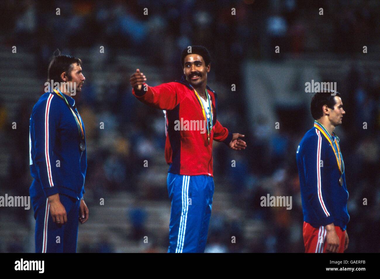 Great Britain's Daley Thompson (c) indicates the size of his achievement in beating USSR's Yuriy Kutsenko (l, silver) and Sergey Zhelanov (r, bronze) to the gold medal Stock Photo