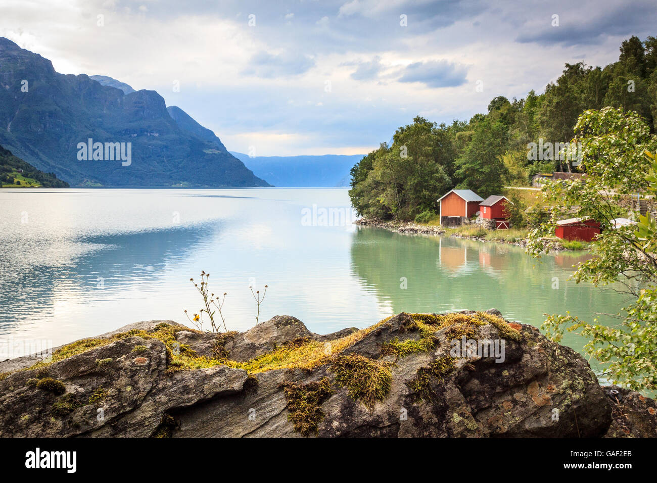 Red boat houses close to a fjord running through steep Norwegian landscape in Luster,, Sogn. Stock Photo