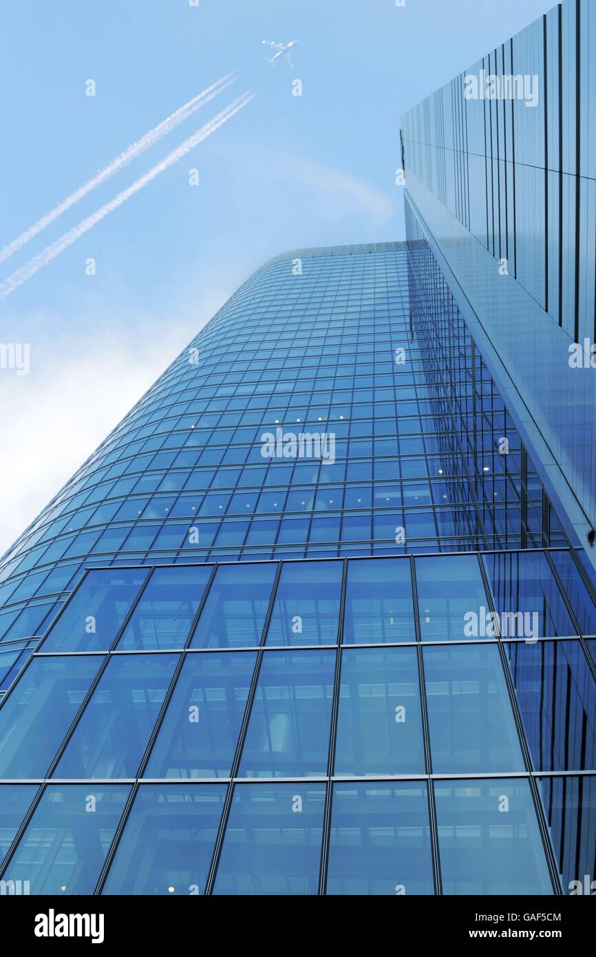 Glassy skyscraper and aircraft in the sky Stock Photo