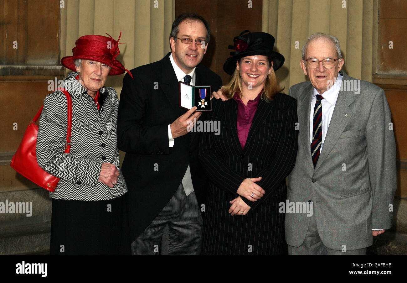 Press Association's Group Picture Editor Martin Keene (C) with mum Pamela Keene (L), Fiancee Laura Kerr and dad John Keene collects his Royal Victorian Order Stock Photo