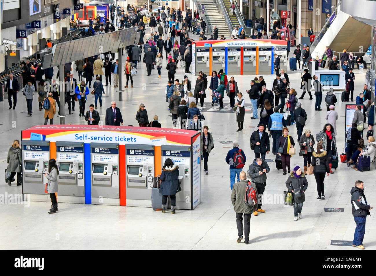 Looking down on passengers & commuters two sets Self Service ticket machines at busy Waterloo train station in Lambeth London England UK Stock Photo