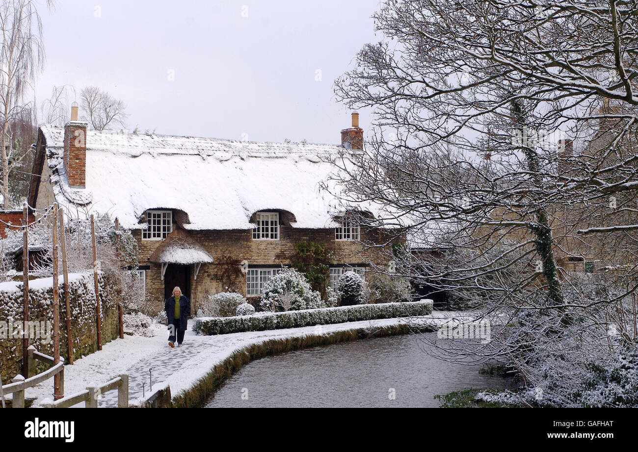 A woman takes a walk beside the stream in the village of Thornton-le-Dale, North Yorkshire, after snow fell early today. Stock Photo