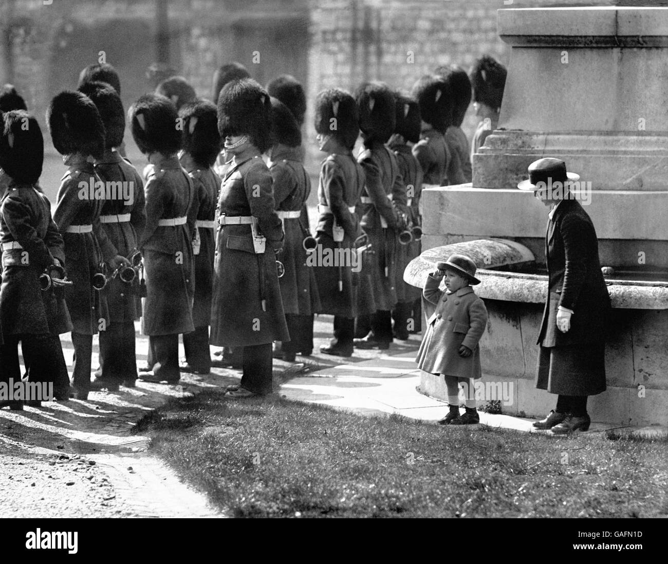 Alexander Ramsey, the grandson of the 13th earl of Dalhousie, stands at salute with his nurse under the Walls of Windsor Castle whilst waiting to watch the Changing of the Guard. Stock Photo