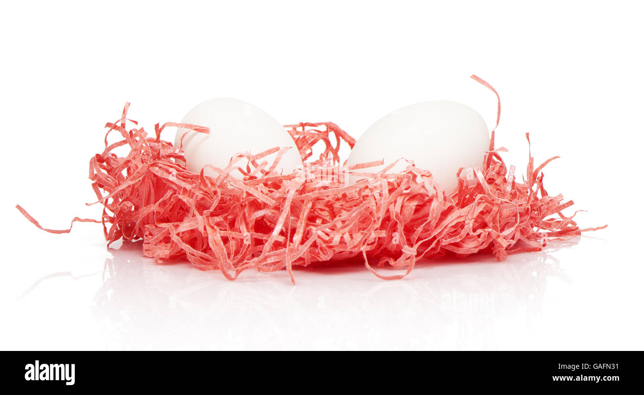 Two white chicken eggs in pink paper nest isolated on white background Stock Photo