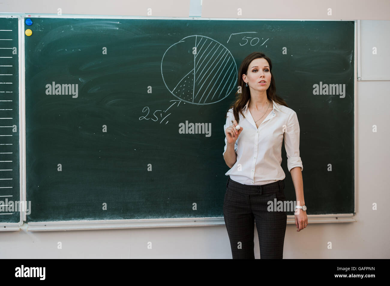Happy businesswoman in front of cogwheel background Stock Photo