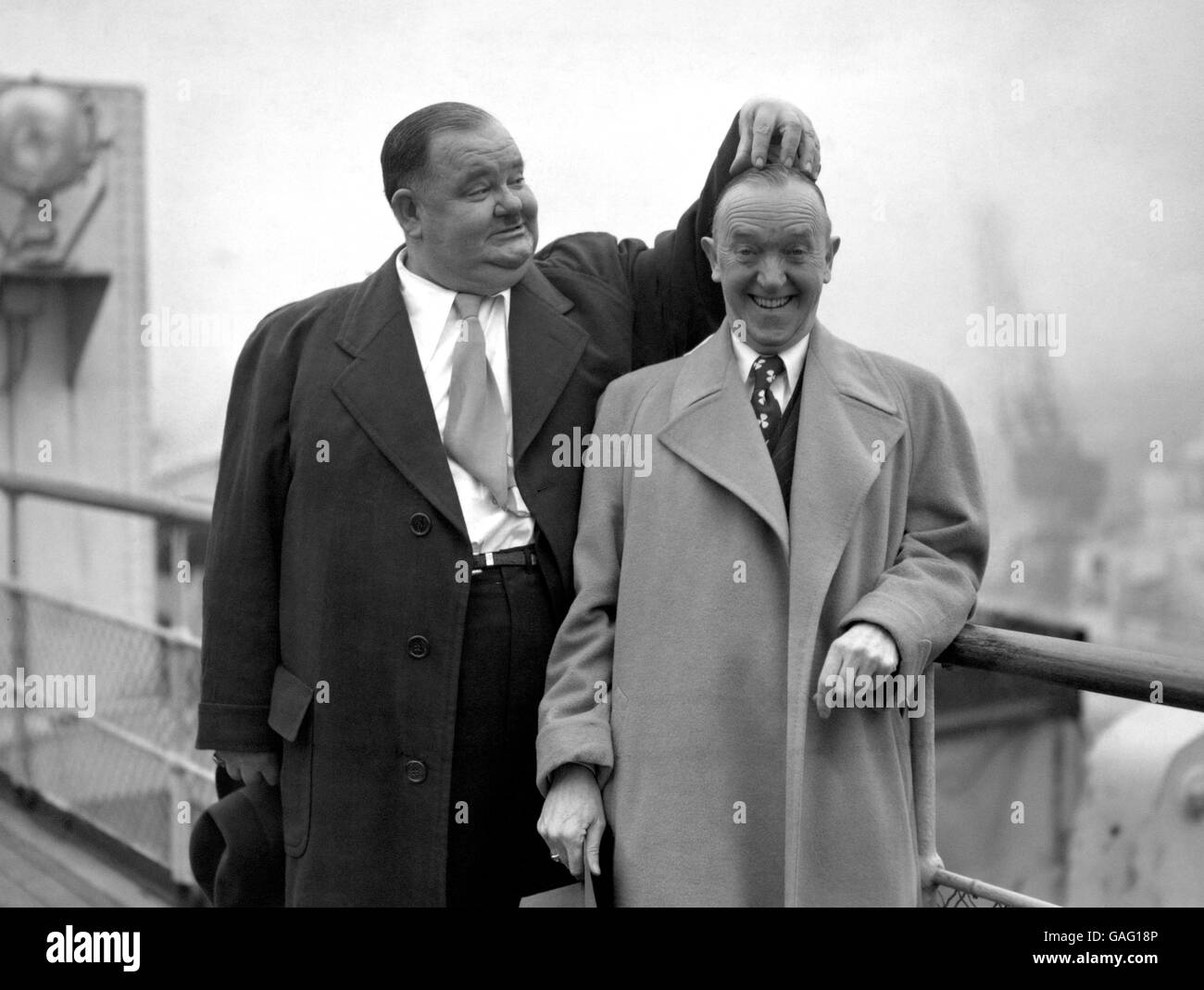 Oliver Hardy scratches the head of Stan Laurel, as the famous pair pose on the 'Queen Elizabeth' at Southampton. It is their first visit to the country since 1932. Stock Photo
