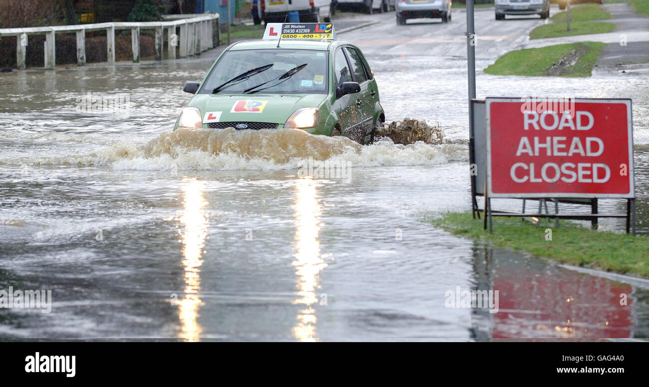 A learner driver car splashes through the floodwaters in the village of Elvington, North Yorkshire today. Stock Photo