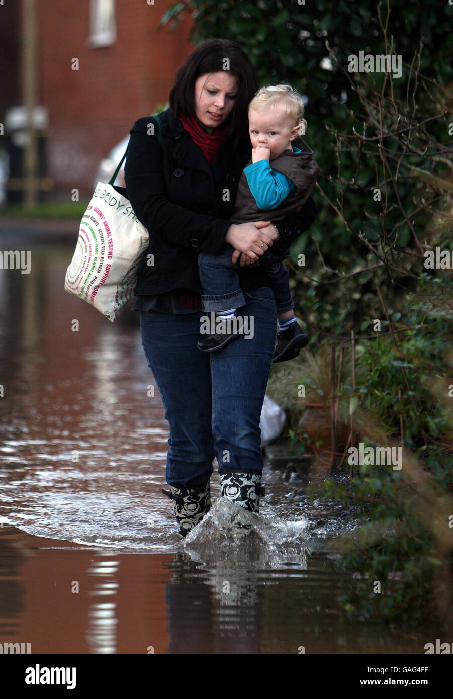 Continuing flooding in UK. A resident of New Street in Upton makes her way home through the floods. Stock Photo