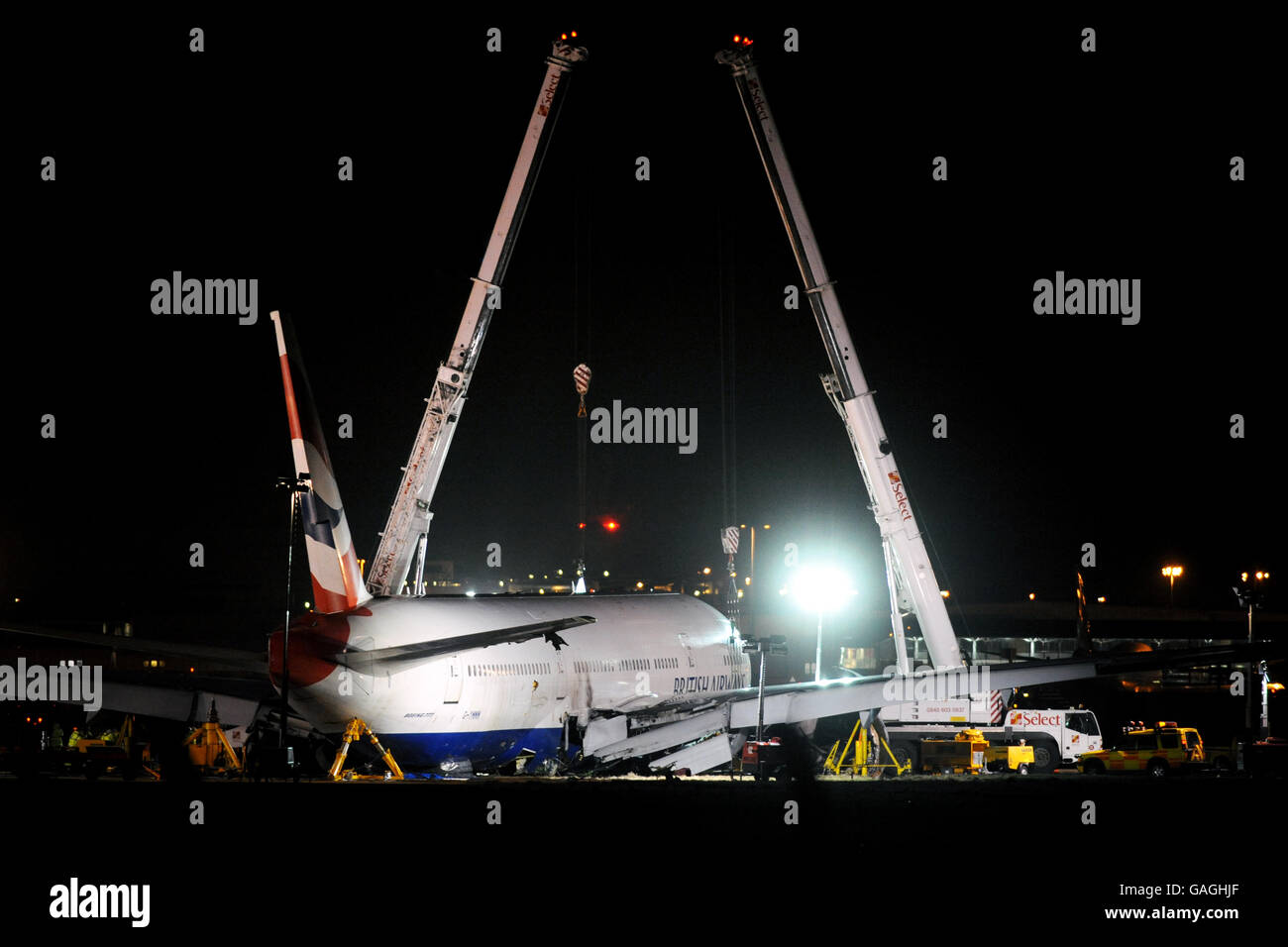 The British Airways Boeing 777 plane that crash landed at Heathrow airport yesterday afternoon, is held up off the ground by two giant cranes this evening. Stock Photo