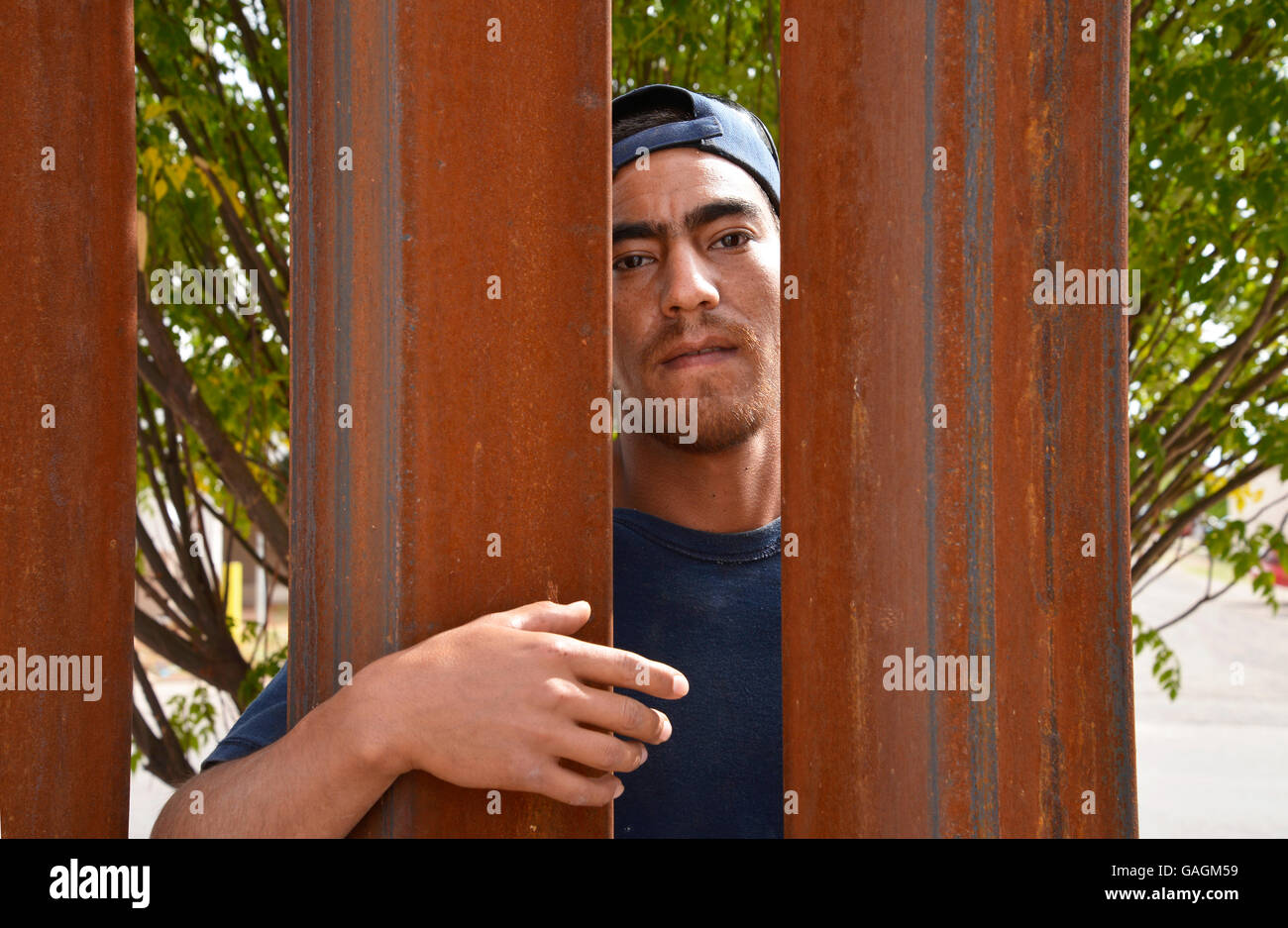 A man in Agua Prieta, Sonora, Mexico, looks through the border wall in to Douglas Arizona, USA. Stock Photo