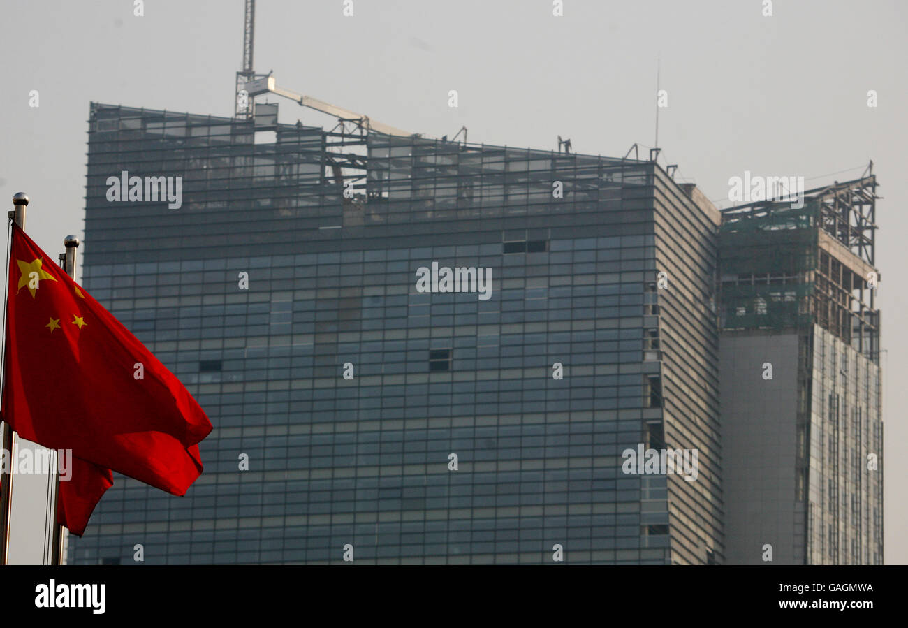 Beijing National Olympic Stadium Feature. Stock Picture of the Chinese flag flying in the wind with building work going on in the background Stock Photo