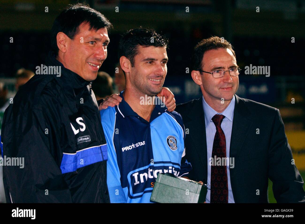 Wycombe Wanderers' Jason Cousins receives a gift from his manager Lawrie Sanchez and Celtic's manager Martin O'Neill Stock Photo