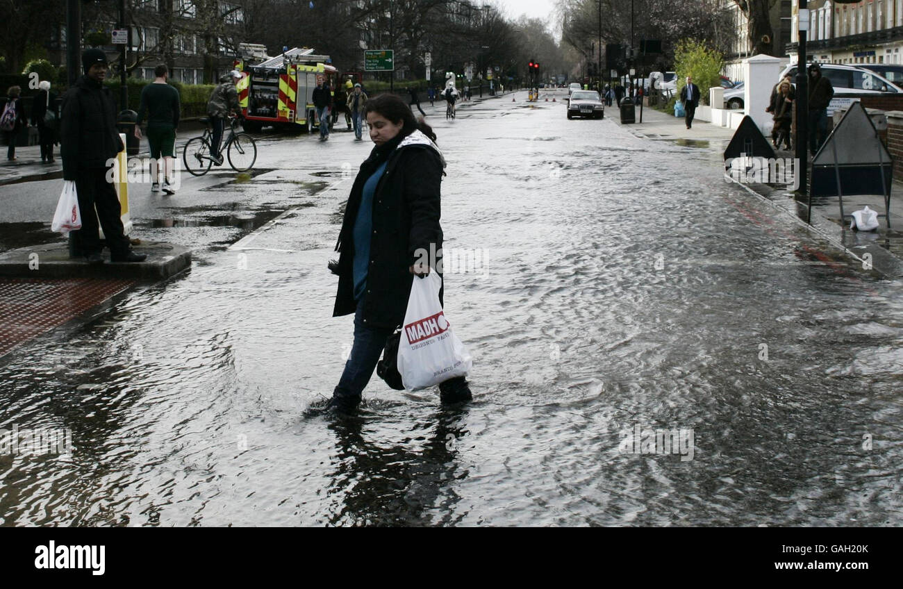 People wade through water after a burst water main in Edgware Road, London. Stock Photo